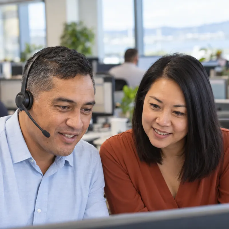 Illustrative image of two contact-centre staff working together at a desk